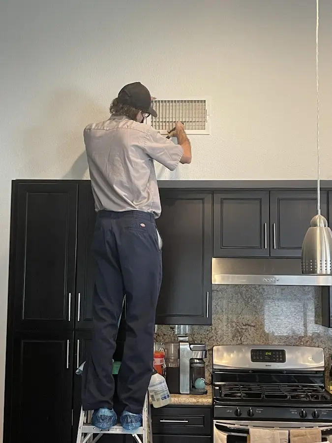 Technician inspecting an air vent during HVAC service in Bailey's Crossroads